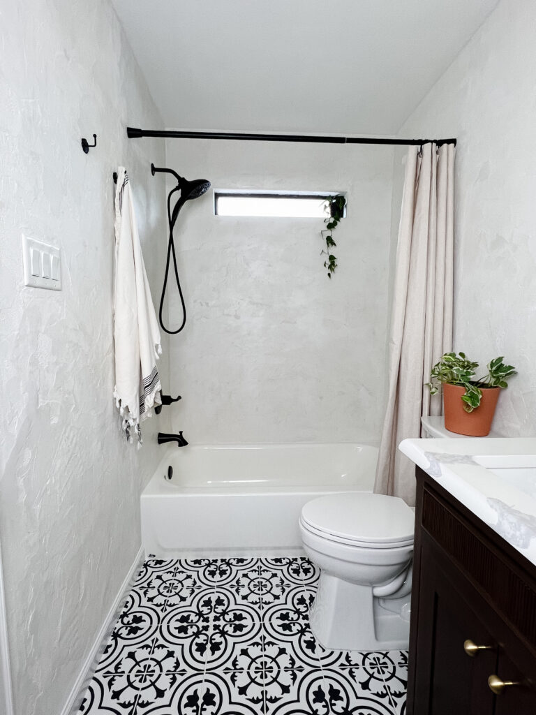 Full view of DIY microcement bathroom with patterned tile floor, bathtub, and modern vanity.