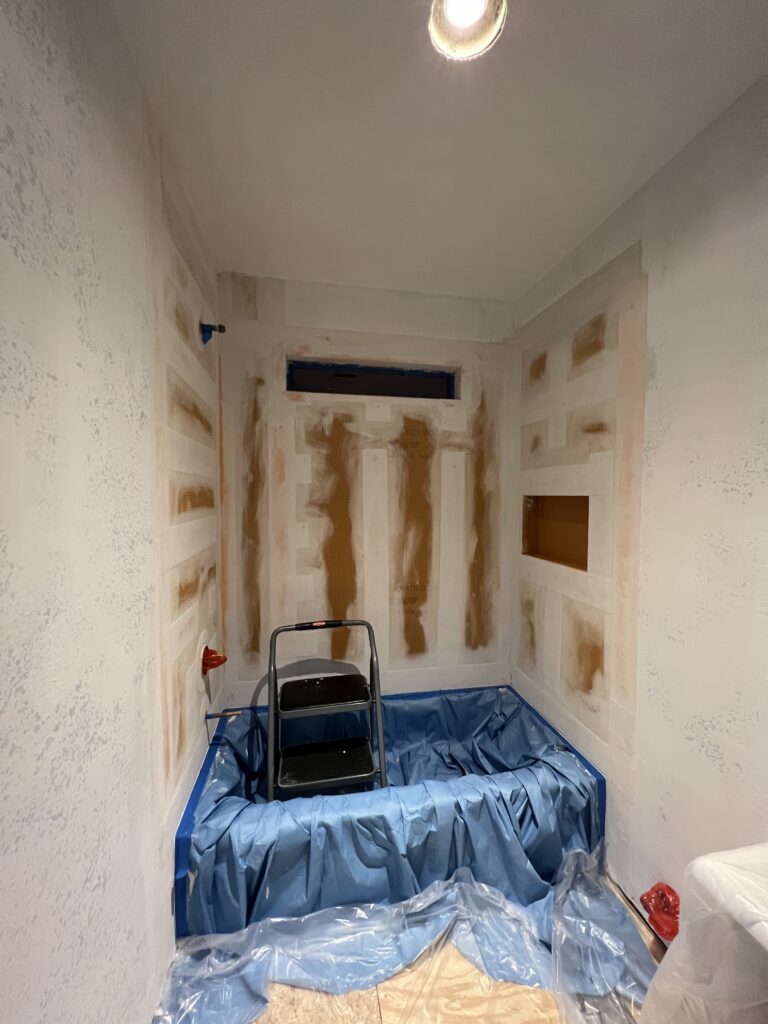 Guest bathroom walls prepped, tub and floor covered with plastic sheeting.