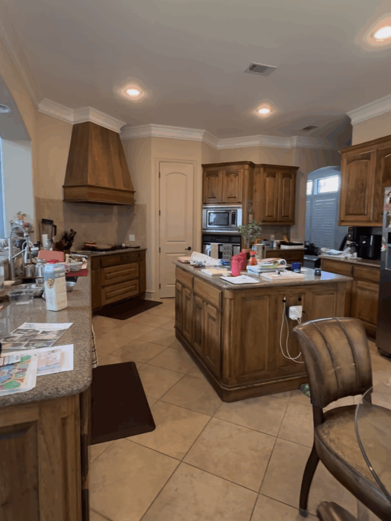 Before photo of dated kitchen with beige walls, dark cabinets, and cluttered counters before the DIY kitchen makeover.