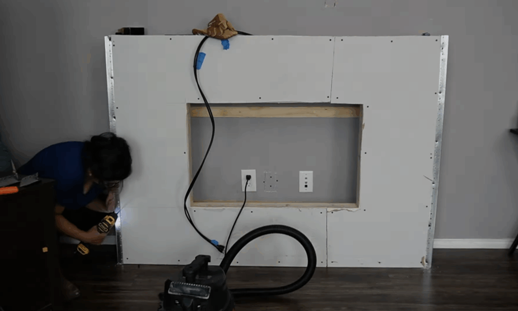 Securing metal corner bead along the edges of the drywall fireplace structure for crisp, finished corners.