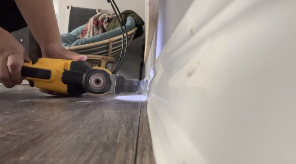 Cutting away baseboards with a Dewalt multi-tool to make space for the DIY electric fireplace frame.