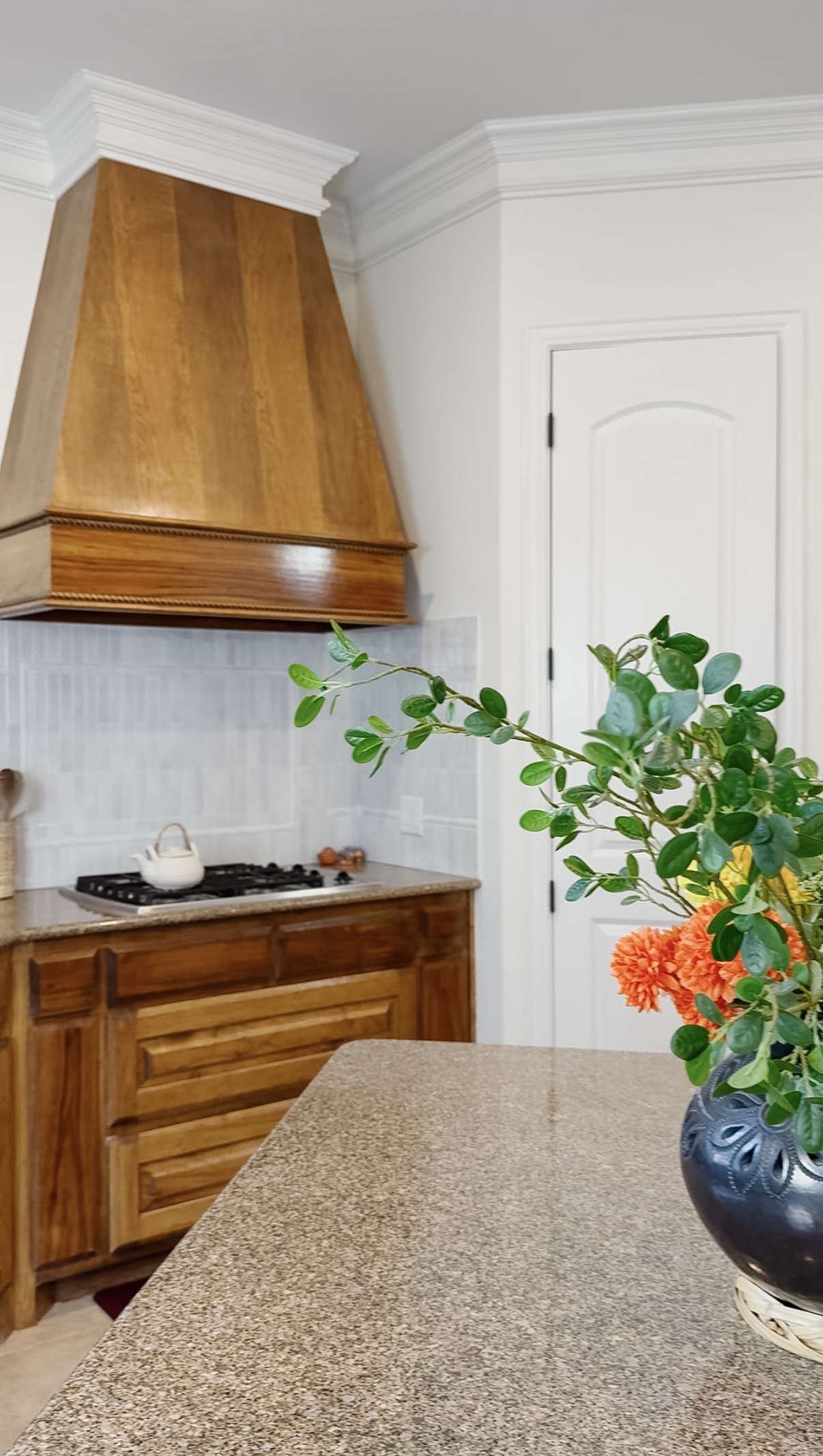 Updated kitchen corner with wooden vent hood, new peel-and-stick backsplash, and bright white painted walls
