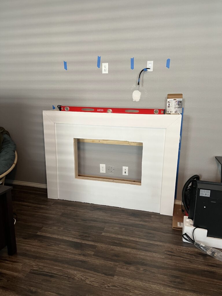 Framed and drywalled electric fireplace wall with outlet and wiring complete, ready for the fireplace insert.