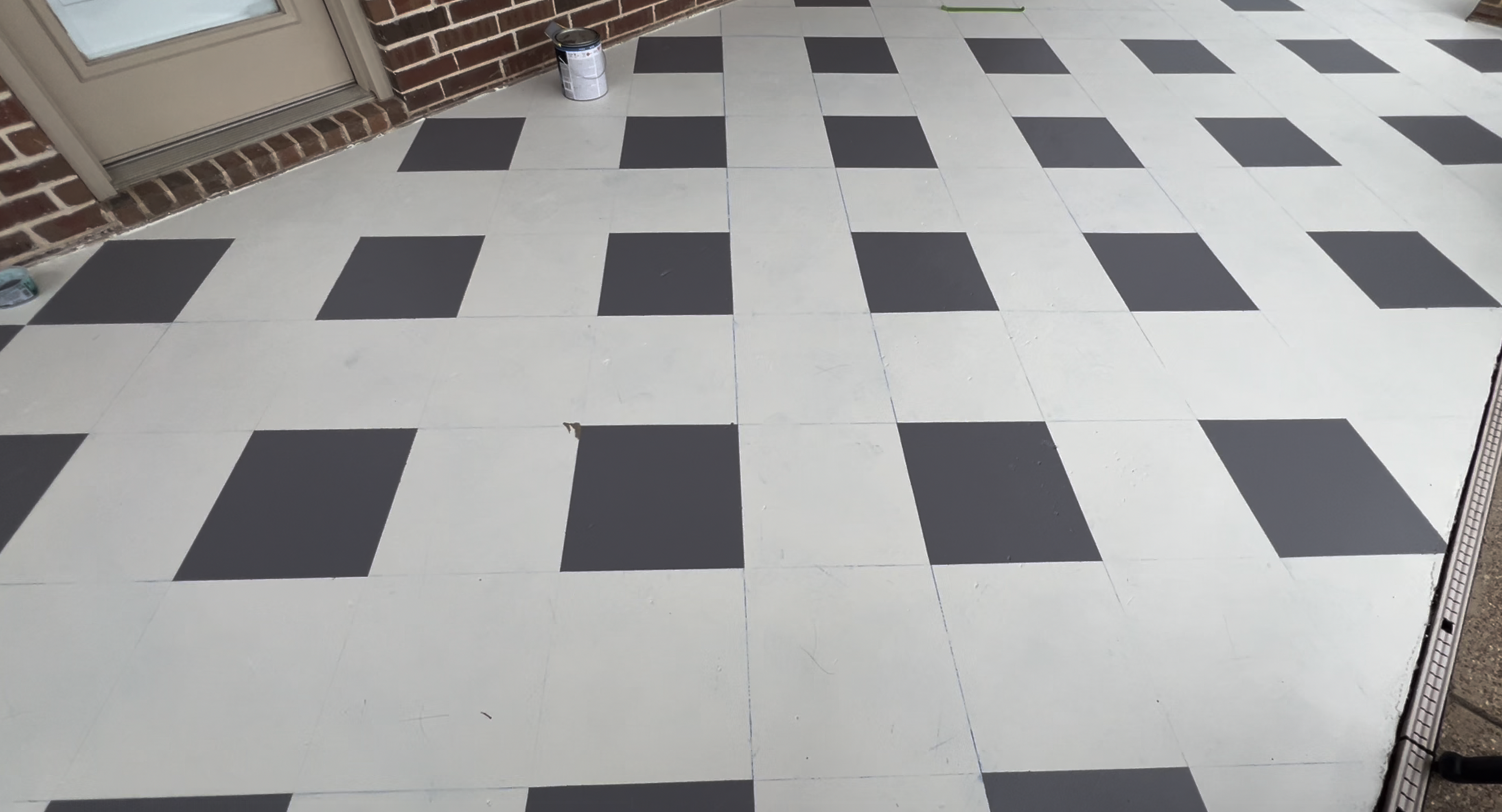 Patio floor with the first set of gray squares painted before adding final tape lines.
