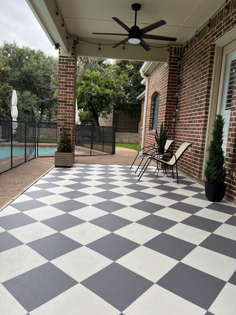 Long view of the gray and white checkered patio with outdoor furniture and plants.