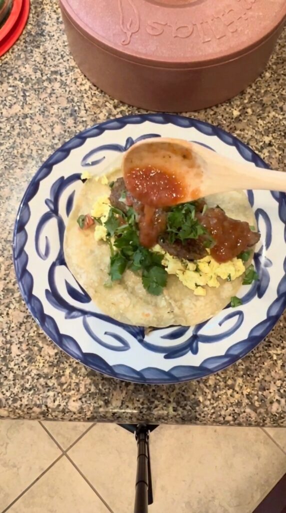 Adding salsa and cilantro to a vegan breakfast burrito with tofu scramble