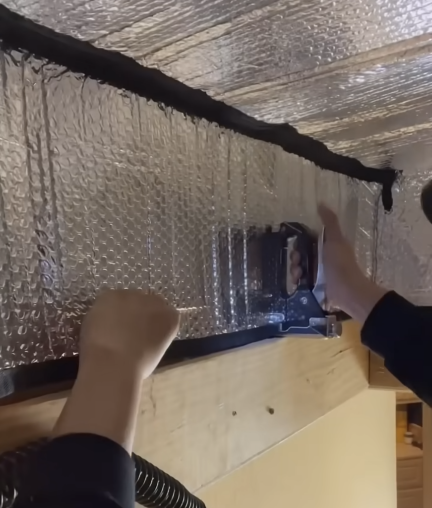 stapling a foil bubble wrap attic insulation cover into the attic hatch