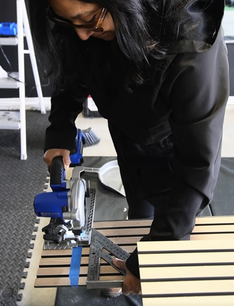 Woman using a Kobalt circular saw and speed square to cut a fluted MDF wall panel to size