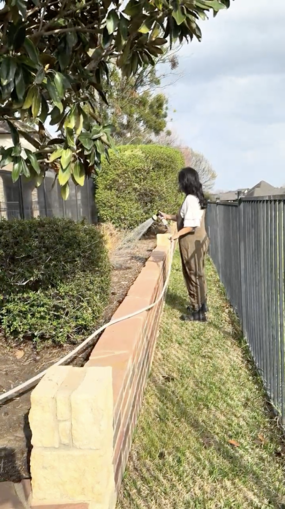 Watering hedges and landscaping along a brick retaining wall using the Hoselink retractable garden hose