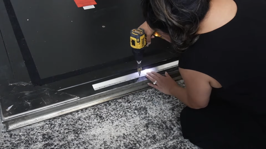 Attaching an Ook French cleat bracket to the back of a large heavy mirror laid face down on the floor using a DeWalt drill