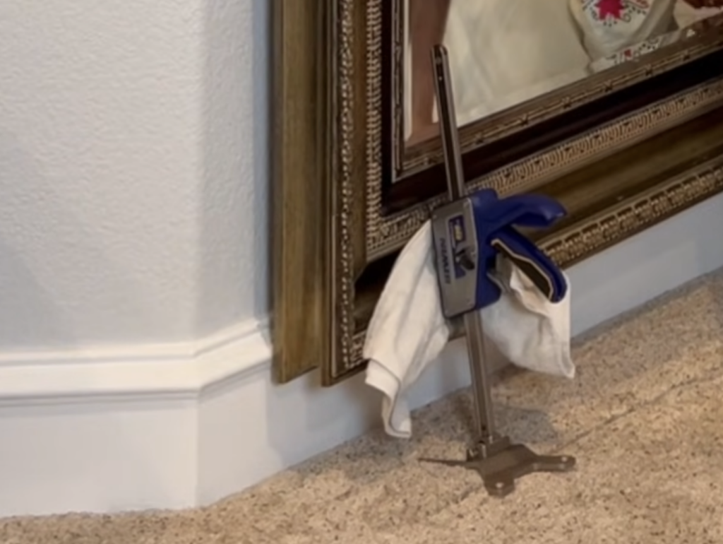 Irwin Quick Lift construction jack lifting the bottom of a heavy framed mirror into place during a French cleat installation