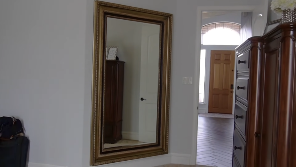 Large gold-framed heavy mirror successfully hung on a drywall wall using a French cleat system in a Texas home entryway